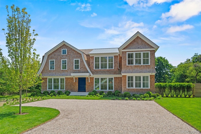 Unparalleled Shingle-style home featuring a front yard and spacious driveway