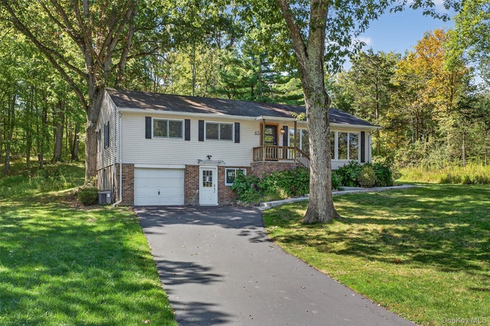 View of front of home with brick siding, driveway, a garage, and a front lawn