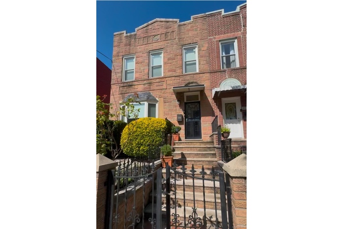 View of front facade with a fenced front yard, a gate, and brick siding