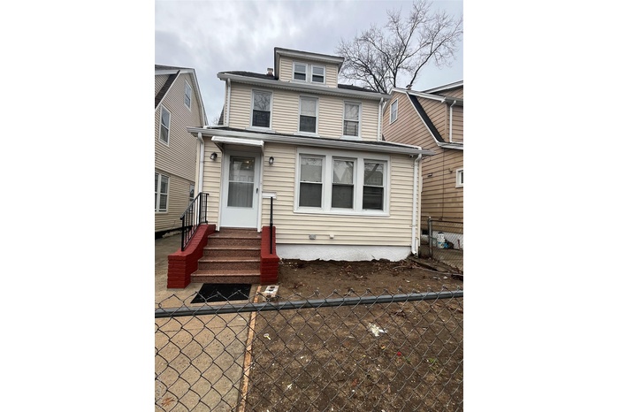 American foursquare style home with entry steps and fence