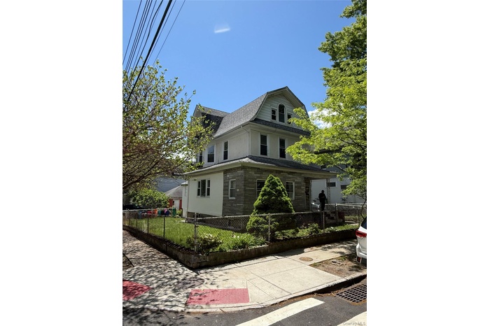 View of front of property with a gambrel roof, roof with shingles, a fenced front yard, and stucco siding