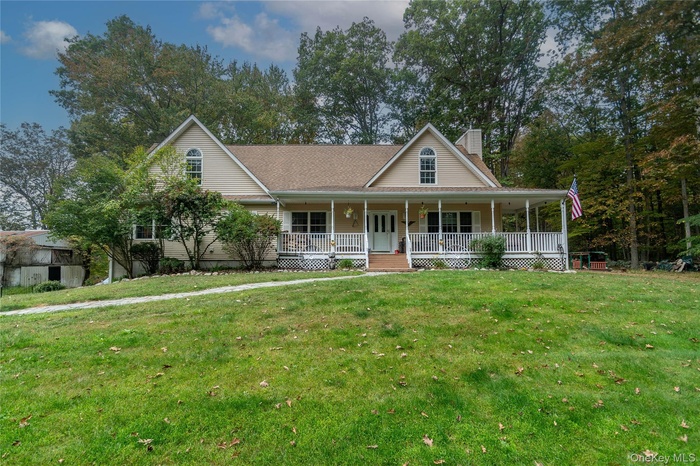 Farmhouse-style home featuring a porch, a front lawn, a chimney, and a shingled roof