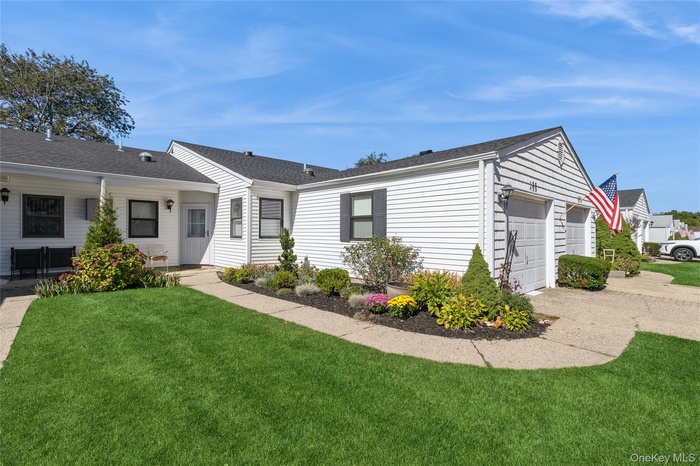 A ranch-style condo with a front lawn, tasteful landscaping, and an attached garage.