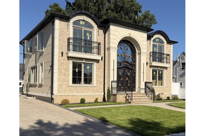 View of front building with a balcony, brick siding, and a front lawn