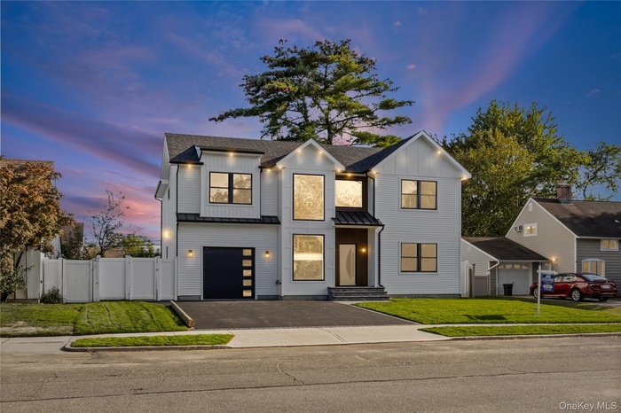 Modern farmhouse style home featuring board and batten siding, driveway, a standing seam roof, a metal roof, and a garage