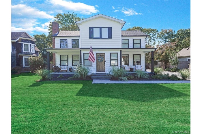 View of front facade featuring covered porch, a front lawn, and a chimney