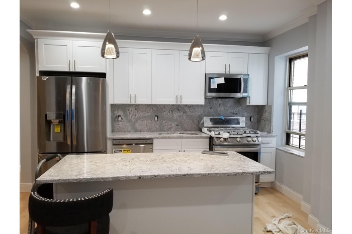 Kitchen with backsplash, white cabinetry, light stone countertops, a kitchen breakfast bar, and ornamental molding