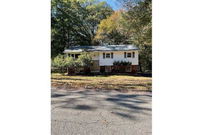 Split foyer home with view of scattered trees and brick siding