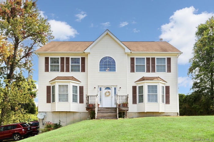 Colonial-style house featuring a front lawn
