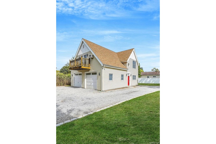 View of front facade with roof with shingles, a garage, a front lawn, and gravel driveway