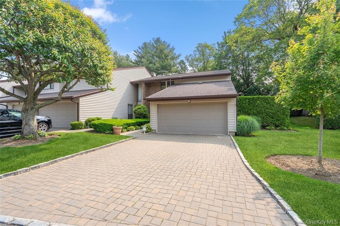 View of front of property with a front lawn and decorative driveway