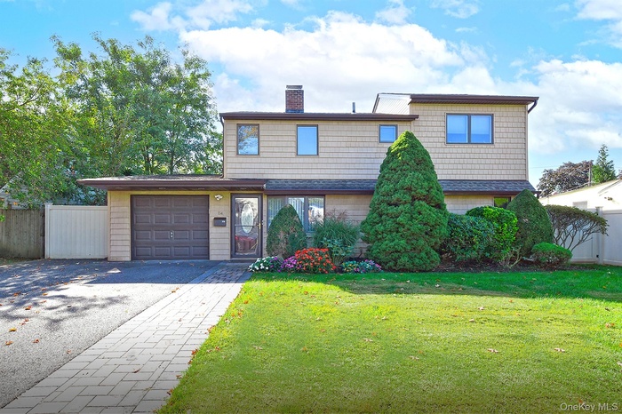 Traditional home featuring driveway, a chimney, and an attached garage