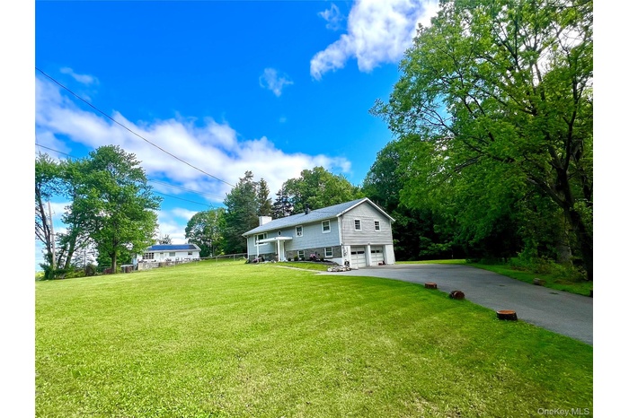View of front of property featuring a garage, driveway, and a front lawn