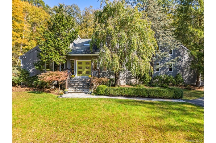 View of property hidden behind natural elements featuring a porch and a front yard