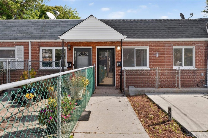 View of front facade with a fenced front yard, brick siding, and a shingled roof