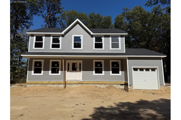 Traditional-style home with covered porch, a shingled roof, and a garage