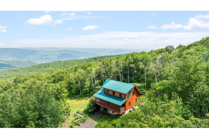 Aerial view of property and surrounding area with a heavily wooded area