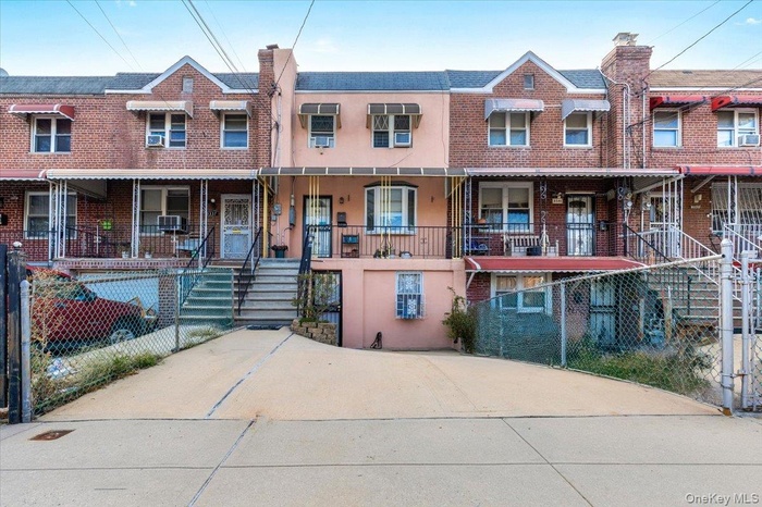 View of front facade featuring stucco siding, a fenced front yard, stairway, brick siding, and a porch