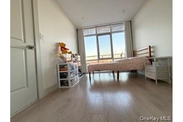 Bedroom with a wall of windows and light wood-style floors