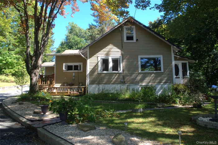 Rear view of house featuring a wooden deck, a yard, and a chimney