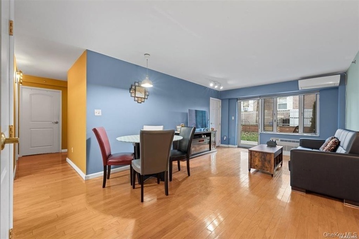 Dining area with light wood-style floors, a wall mounted AC, and radiator heating unit