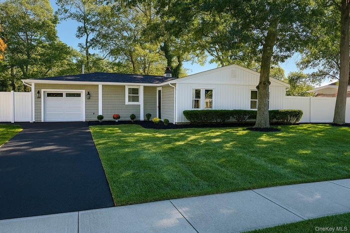 Ranch-style house with a garage, asphalt driveway, board and batten siding, and a chimney