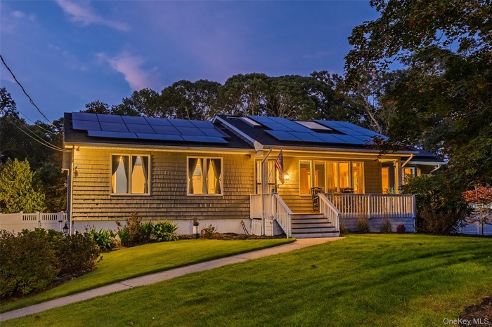 Ranch-style house with covered porch, a front yard, and solar panels