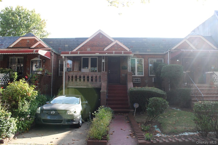View of front of house with stairway, brick siding, and a porch