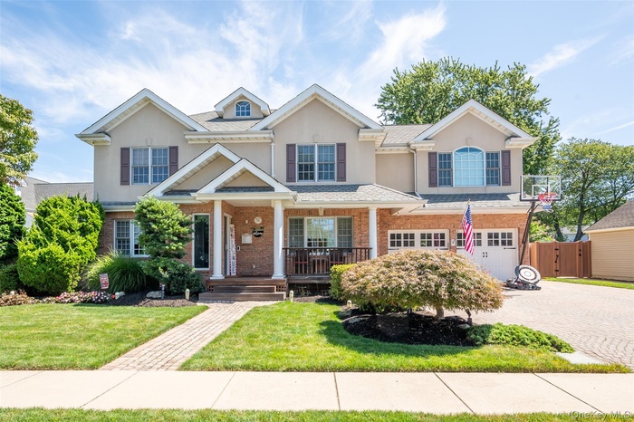 View of front of property featuring a porch, stucco siding, decorative driveway, a front lawn, and brick siding