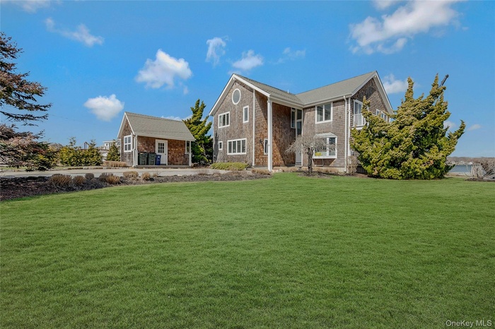 View of front of home with an outbuilding and a front yard