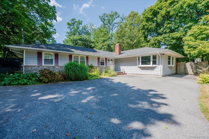 Ranch-style house featuring a chimney and asphalt driveway