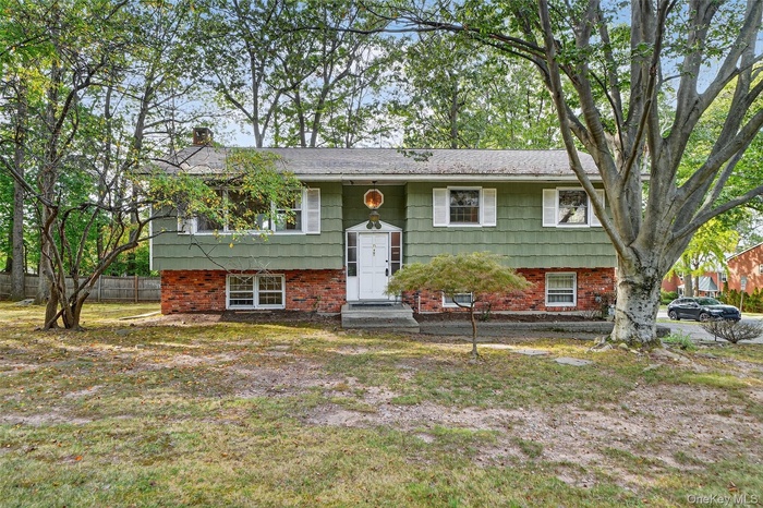 Split foyer home featuring brick siding, a chimney, and entry steps