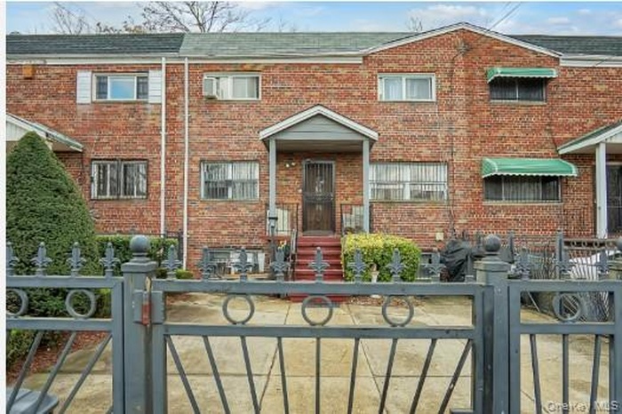 Traditional-style home featuring brick siding, a fenced front yard, and a gate