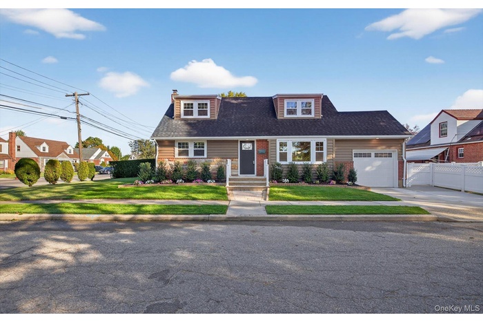 View of front of house with driveway, a garage, a chimney, and a shingled roof