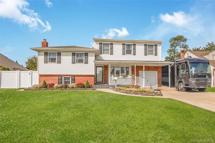 Tri-level home with brick siding, a chimney, a porch, driveway, and an attached garage