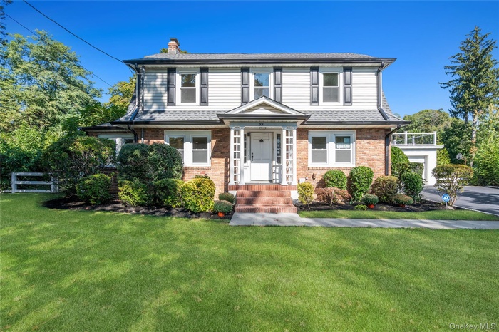 View of front of house featuring a front yard, brick siding, and a chimney