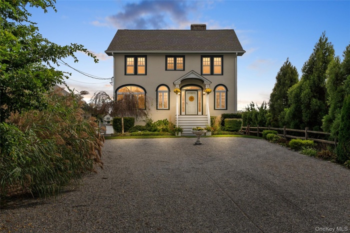 View of front of home featuring stucco siding, driveway, and a chimney