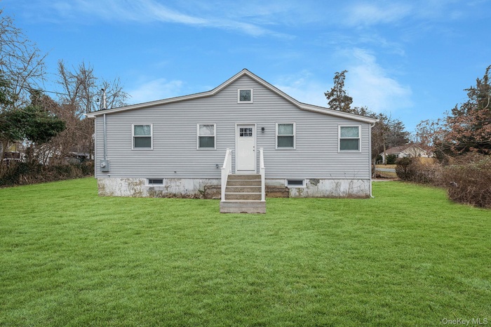 Rear view of property featuring a lawn and entry steps
