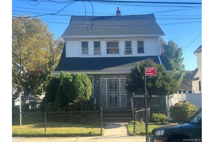 View of front of home with a shingled roof, a fenced front yard, a chimney, and a gate