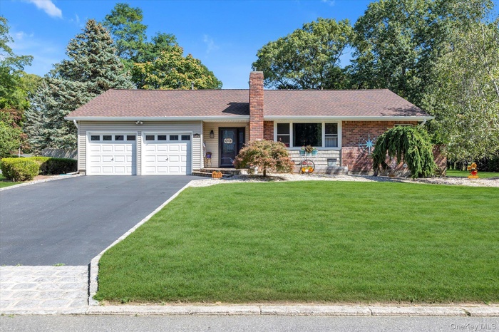 Single story home featuring a front lawn, asphalt driveway, roof with shingles, a garage, and a chimney