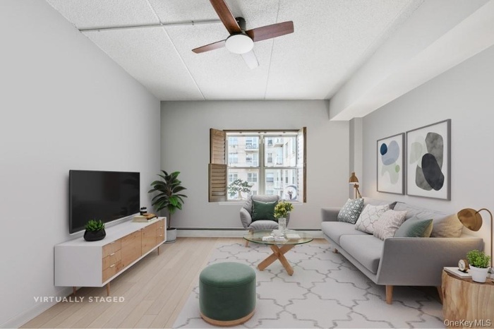 Living area featuring wood finished floors, ceiling fan, and a baseboard radiator