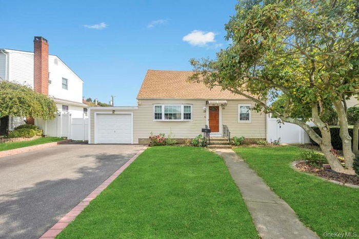 View of front facade with asphalt driveway, a garage, and a shingled roof