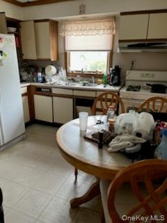 Kitchen featuring light countertops, white appliances, and range hood