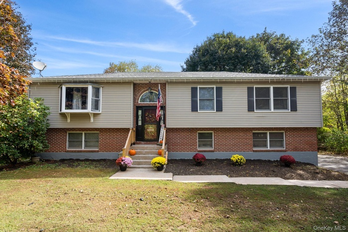 Split foyer home featuring a front lawn and brick siding
