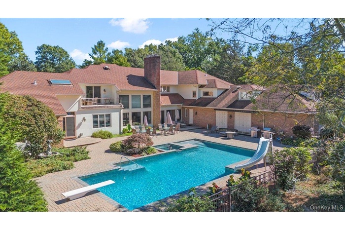 View of pool featuring a balcony, a diving board, a patio area, a water slide, and a pool with connected hot tub