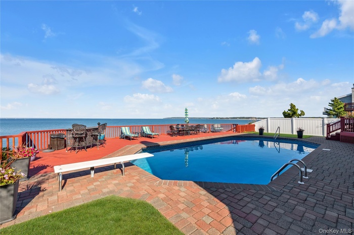 View of pool featuring a water view, a diving board, a patio, and outdoor dining area