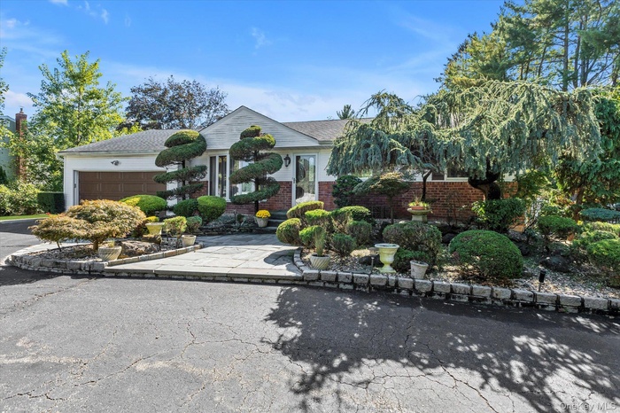 View of front of property featuring asphalt driveway, a garage, roof with shingles, and brick siding