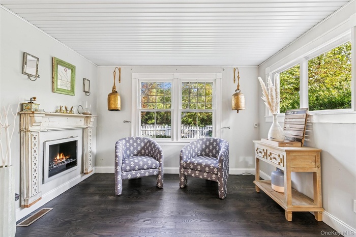 Living area with healthy amount of natural light, a lit fireplace, and dark wood-type flooring
