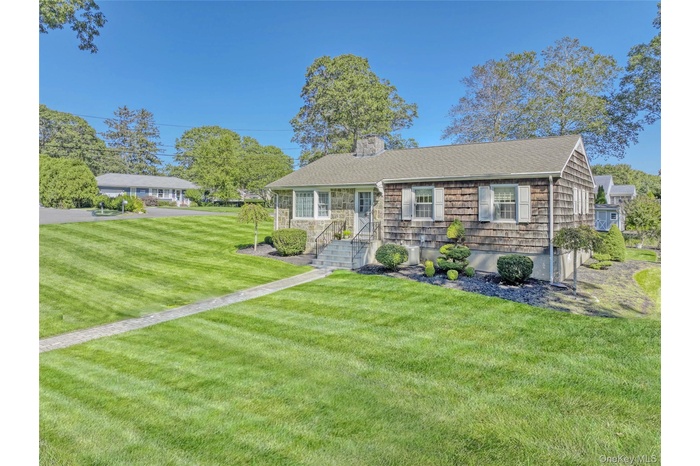 View of front of property featuring a front yard, a chimney, and roof with shingles