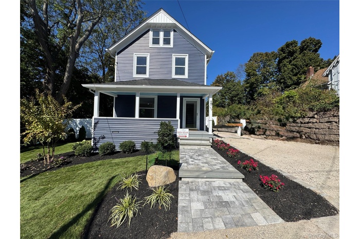 American foursquare style home featuring covered porch, a front yard, and roof with shingles